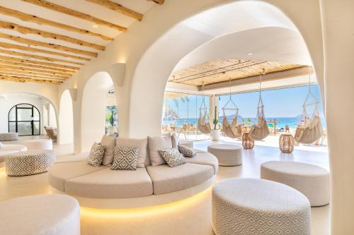 サン・ホアン・デ・ラブリチャにあるEl Somni Ibiza Dream Hotel by Grupotelの白い家具付きのリビングルームが備わり、海の景色を望めます。