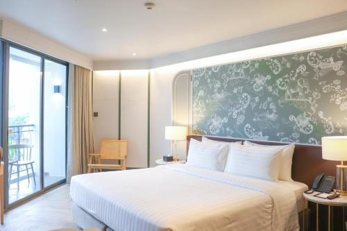 a hotel room with a bed and a green wall at The Quarter Chaophraya by UHG in Bangkok