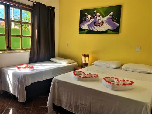 two beds in a room with flowers on them at Capoeira Village in Porto Seguro