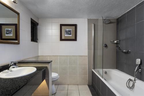 a bathroom with a sink and a tub and a toilet at Kruger Gate Hotel in Skukuza