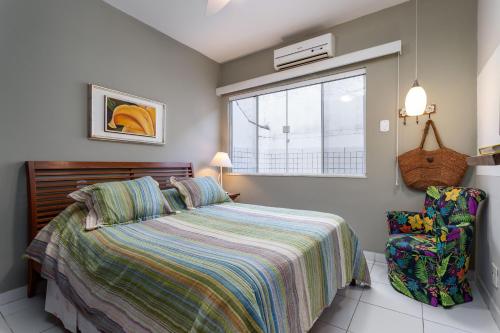 a bedroom with a bed and a window and a chair at Apart Hotel Pet Friendly em Búzios in Búzios