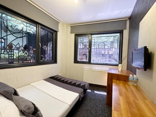 a room with two beds and a tv and two windows at Black Art Otel in Istanbul