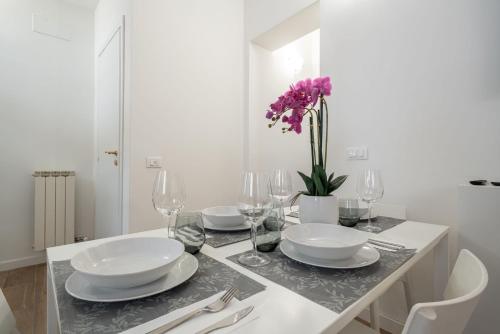 a white table with plates and glasses and a vase with purple flowers at Suite Ravà - San Marco with pool in Venice