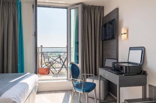 ベルサイユにあるオテル ベルサイユ シャンティエのベッド、デスク、窓が備わるホテルルームです。