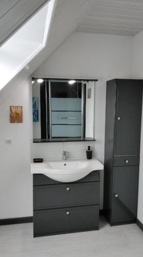 une salle de bain avec un lavabo et un miroir dans l'établissement La Maison Bleue Normande, à Étretat