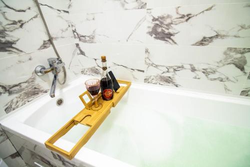a bathroom with a bath tub with a tray with wine glasses at AB Apart Business 64305 in Astana