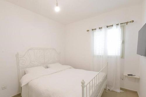 a white bedroom with a white bed and a window at Modern 2BR APT Golf Residence in Eilat