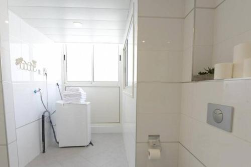 a white bathroom with a toilet and a window at Modern 2BR APT Golf Residence in Eilat
