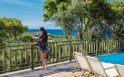 a woman standing on a balcony next to a pool at Lofos Soilis in Tragaki