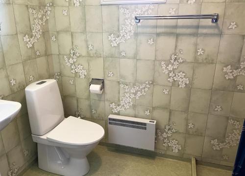 a bathroom with a toilet and flowers on the wall at Red cozy cottage with sea view in Mörbylånga