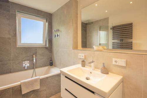 a bathroom with a sink and a mirror and a tub at SweetHome - DAH03 - LUXUS PUR Apartment, Küche, TV in Dachau