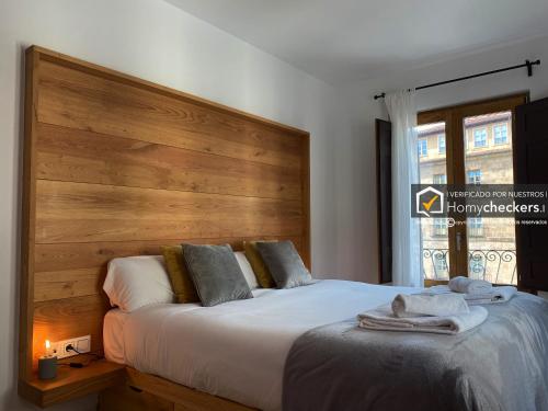 1 dormitorio con 1 cama grande y cabecero de madera en HomyAT Poeta Iglesias 1, Plaza Mayor, en Salamanca