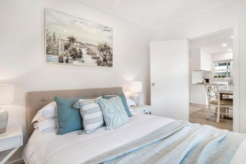 a bedroom with a bed with blue and white pillows at Sur La Mer Semaphore in Semaphore