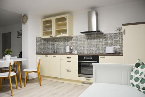 a kitchen with white cabinets and a table and chairs at Apartmán Květinový Dům in Hluk