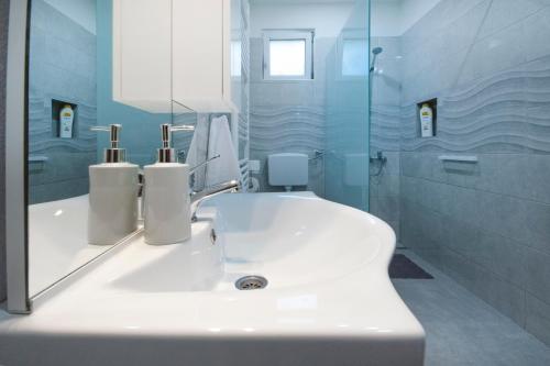 bagno bianco con lavandino e specchio di Apartman Rita a Slunj