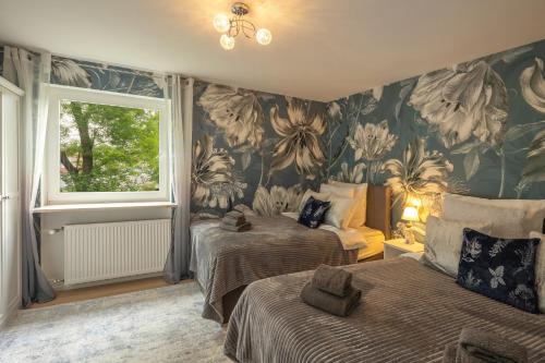 um quarto com 2 camas e um papel de parede florido em SweetHome - DAH03 - LUXUS PUR Apartment, Küche, TV em Dachau