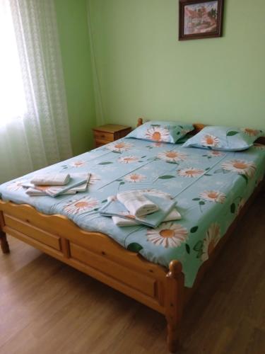 a bed with a blue comforter with flowers on it at Къща за гости Ганчеви in Sozopol