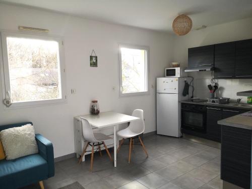 a kitchen with a white table and a white refrigerator at Aux portes de Nantes, 2 pièces moderne et confortable in Carquefou