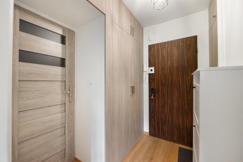 a walk in closet with wooden doors and wooden floors at Ochota Standard Apartment in Warsaw