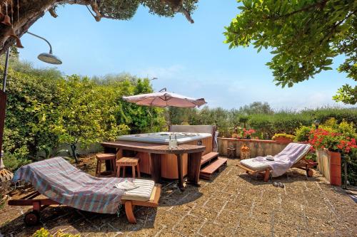 a patio with a table and an umbrella and chairs at Ca dei Tati -Citr 1181 with Jacuzzi in Imperia