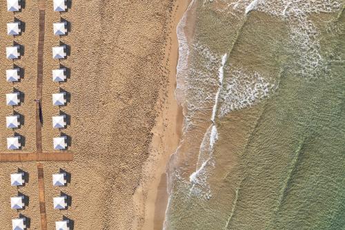 an overhead view of a beach with a group of umbrellas at Domes of Corfu, Autograph Collection in Glyfada