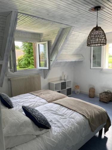 une chambre avec un grand lit et deux fenêtres dans l'établissement GITE 4 MN DE LA mer et cabourg, cheminée, table de ping pong, balançoire, à Varaville
