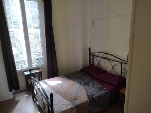 a bedroom with a bed and a large window at Hôtel Lyonnais in Nice