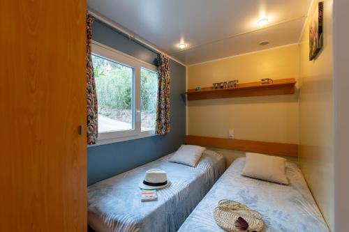 two beds in a room with a window at La Doucette, mobil-home climatisé au cœur du vignoble et à 50m de la mer in Hyères
