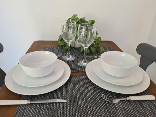 a wooden table with plates and wine glasses on it at Cosy Cottage for work or leisure, RD&E 20min walk, easy access to city centre in Exeter