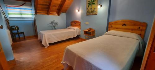 a bedroom with two beds in a room with wooden floors at La Casona in Noja