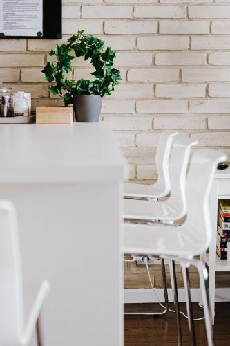 a row of white chairs in front of a white brick wall at Butique Apartman in Balatonlelle