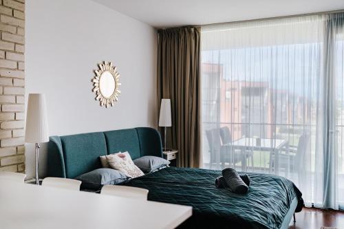 a bedroom with a green bed and a large window at Butique Apartman in Balatonlelle