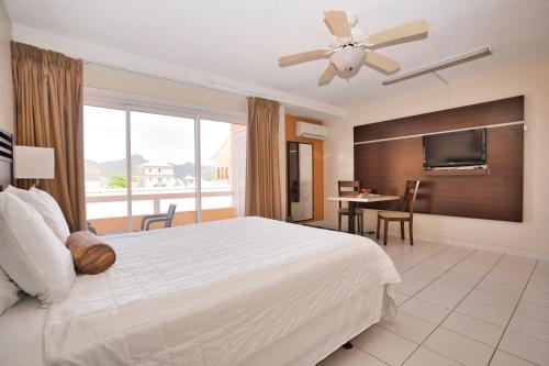 um quarto com uma cama branca e uma televisão de ecrã plano em Horizon View Beach Hotel em Philipsburg