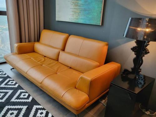 a brown leather couch in a living room with a lamp at Empire Damansara Designer Soho Karaoke & Netflix in Petaling Jaya