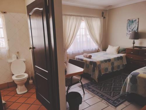 a bedroom with two beds and a toilet and a window at Oregon Place Guest House in Middelburg