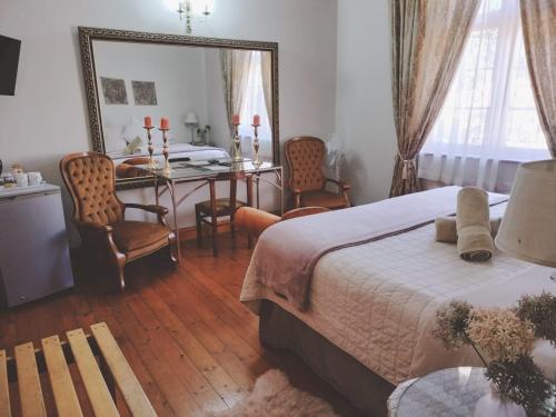 a bedroom with a bed and a table and chairs at Oregon Place Guest House in Middelburg