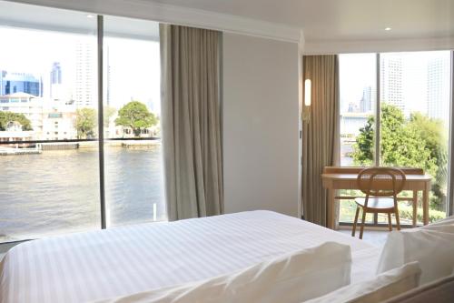 a bedroom with a bed and a view of the water at The Quarter Chaophraya by UHG in Bangkok
