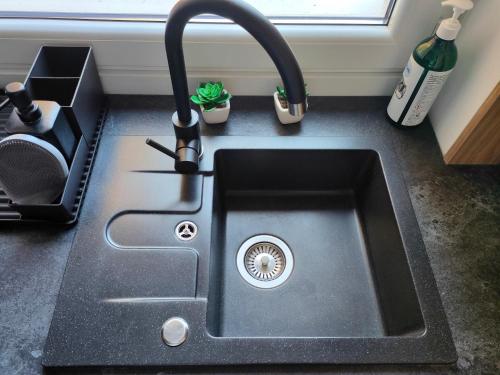 eine schwarze Küchenspüle mit einem Wasserhahn in der Unterkunft Apartament Mineralny in Krynica-Zdrój
