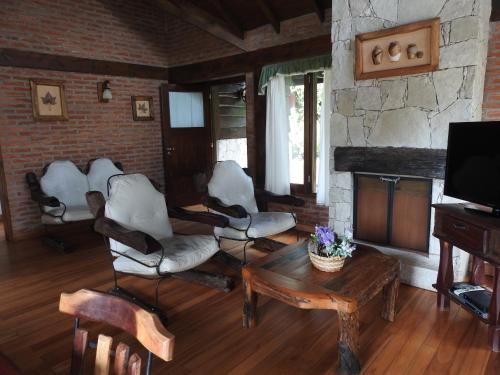 a living room with chairs and a table and a tv at Cabañas Kurumamell in Sierra de los Padres
