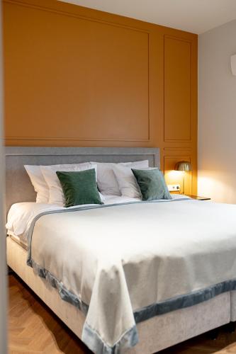 a large bed with white sheets and green pillows at Hotel Gothards in Kuldīga