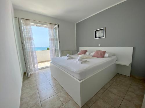a white bedroom with a bed with a view of the ocean at Emanuela 1 in Novalja