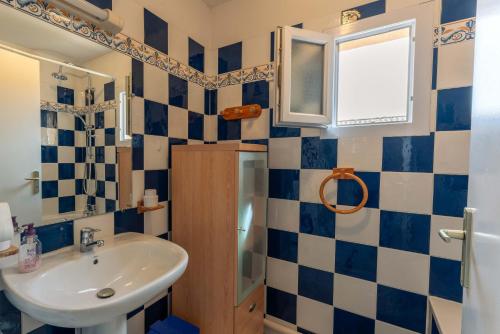een badkamer met blauwe en witte betegelde muren en een wastafel bij Maison avec jardin et Piscine in Vaison-la-Romaine