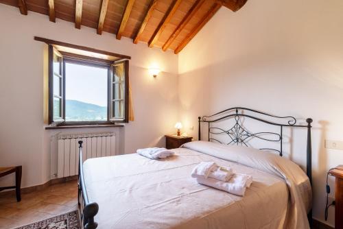 a bedroom with a bed with white sheets and a window at Pugnano Alto - Appartamento Tartufo in Lisciano Niccone