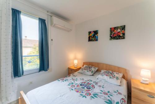 een slaapkamer met een bed met 2 kussens en een raam bij Maison avec jardin et Piscine in Vaison-la-Romaine