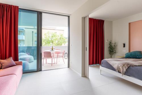 Schlafzimmer mit roten Vorhängen, einem Bett und einem Tisch in der Unterkunft Aparthotel Zefiro com design, large terrace, bike, near beach and thermal in Grado
