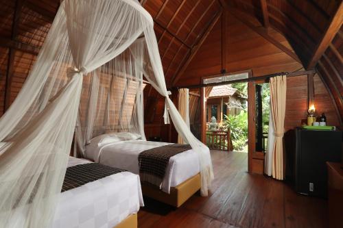 a bedroom with two beds with mosquito nets at The Dukuh Retreat in Tabanan