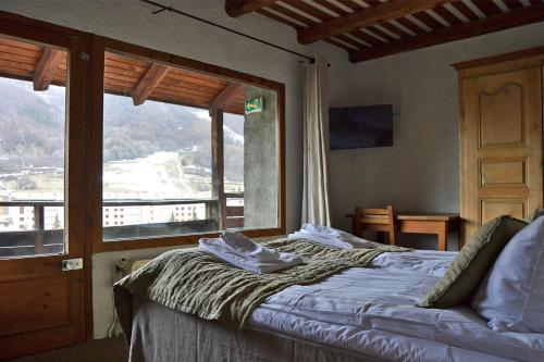 - une chambre avec un lit et une grande fenêtre dans l'établissement Langley Hotel La Vieille Ferme, à La Salle Les Alpes