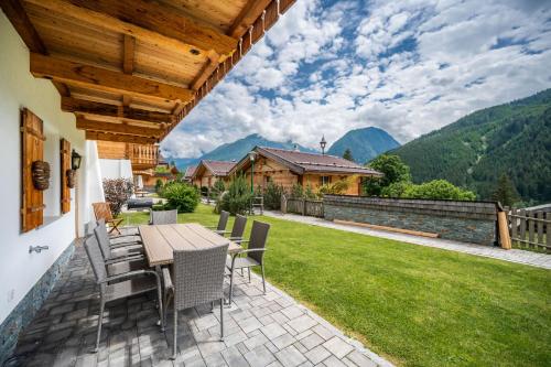 a patio with a table and chairs on a lawn at Chalet #1 am Sonnenhang in Neukirchen am Großvenediger