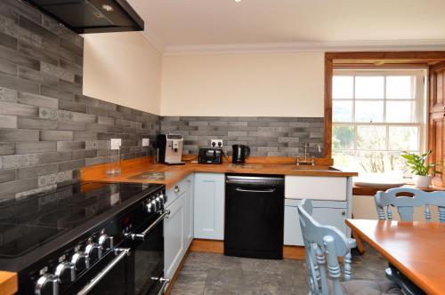 a kitchen with black appliances and a table with chairs at Eckford House in Dunoon