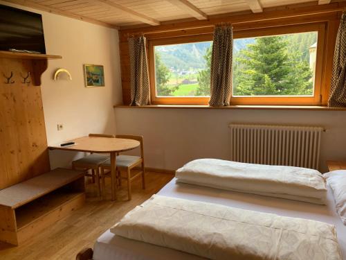 2 Betten in einem Zimmer mit einem Tisch und einem Fenster in der Unterkunft Hotel Alpenhof in Sulden